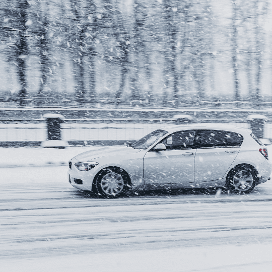 witte auto die aan het rijden is terwijl het sneeuwt witte auto die aan het rijden is terwijl het sneeuwt