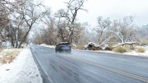 Auto rijdt voorzichtig over natte en besneeuwde weg – veilig rijden tijdens winterse omstandigheden
