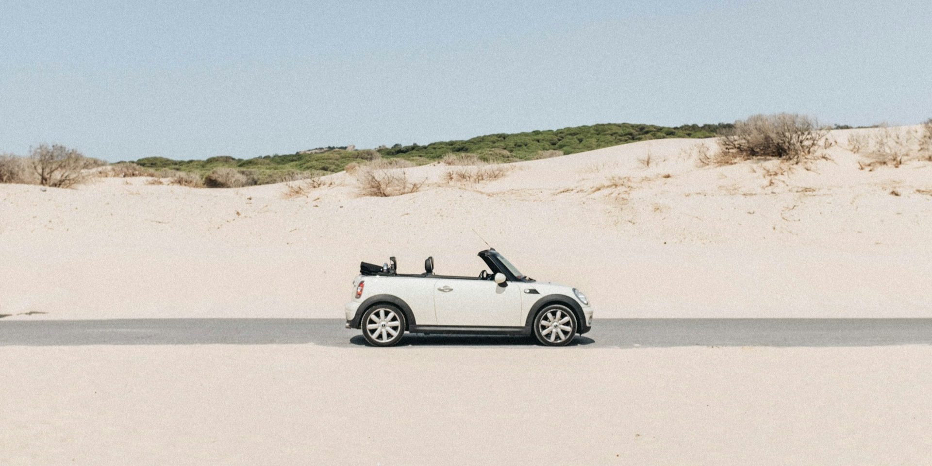 Cabrio rijdt op droge weg door zanderig gebied onder zomerse omstandigheden – veilig rijden in de hitte