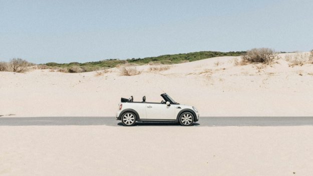 Cabrio rijdt op droge weg door zanderig gebied onder zomerse omstandigheden – veilig rijden in de hitte