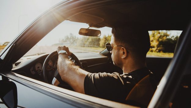 Bestuurder rijdt geconcentreerd tijdens eerste rijjaren, met beide handen aan het stuur in zonnige omstandigheden