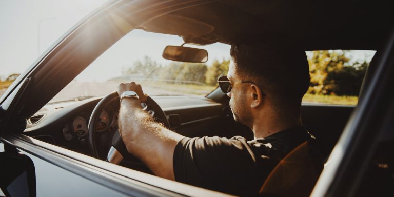 Bestuurder rijdt geconcentreerd tijdens eerste rijjaren, met beide handen aan het stuur in zonnige omstandigheden