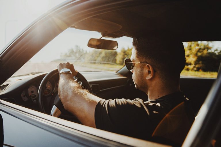 Bestuurder rijdt geconcentreerd tijdens eerste rijjaren, met beide handen aan het stuur in zonnige omstandigheden